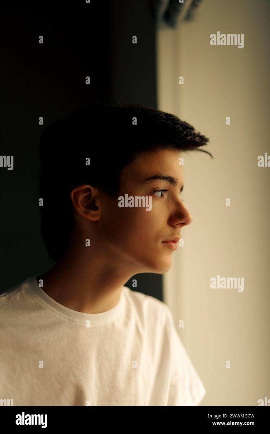 Ritratto di un adolescente che guarda attraverso la finestra Foto Stock