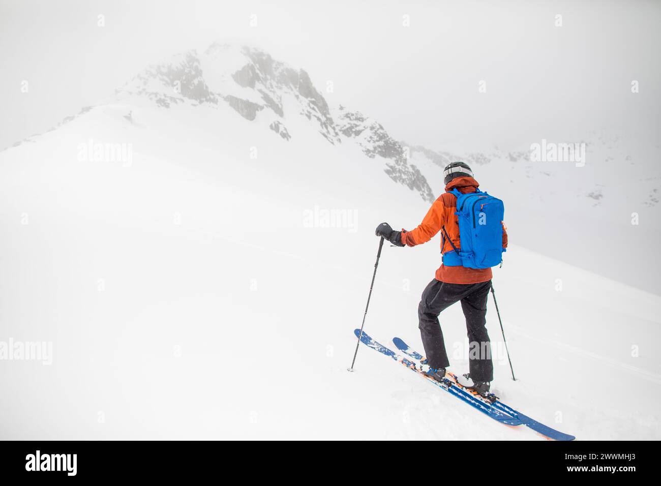 Lo sciatore di fondo si avvicina alla vetta della montagna in quasi bianco Foto Stock