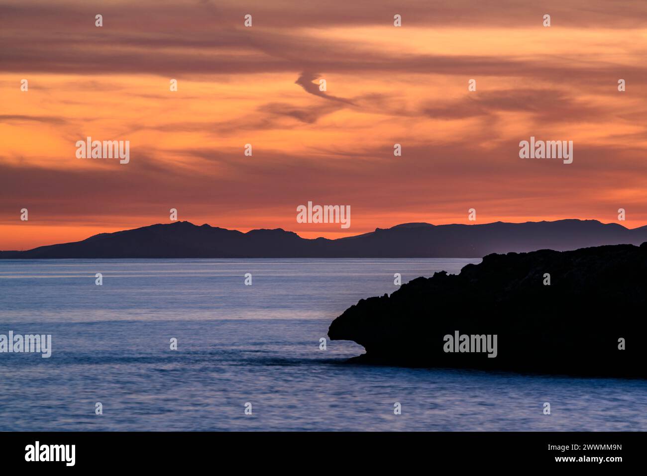Montagne orientali dell'isola di Maiorca viste da Capo Cap d'Artrutx, a Minorca, al tramonto invernale (Minorca, Isole Baleari, Spagna) Foto Stock