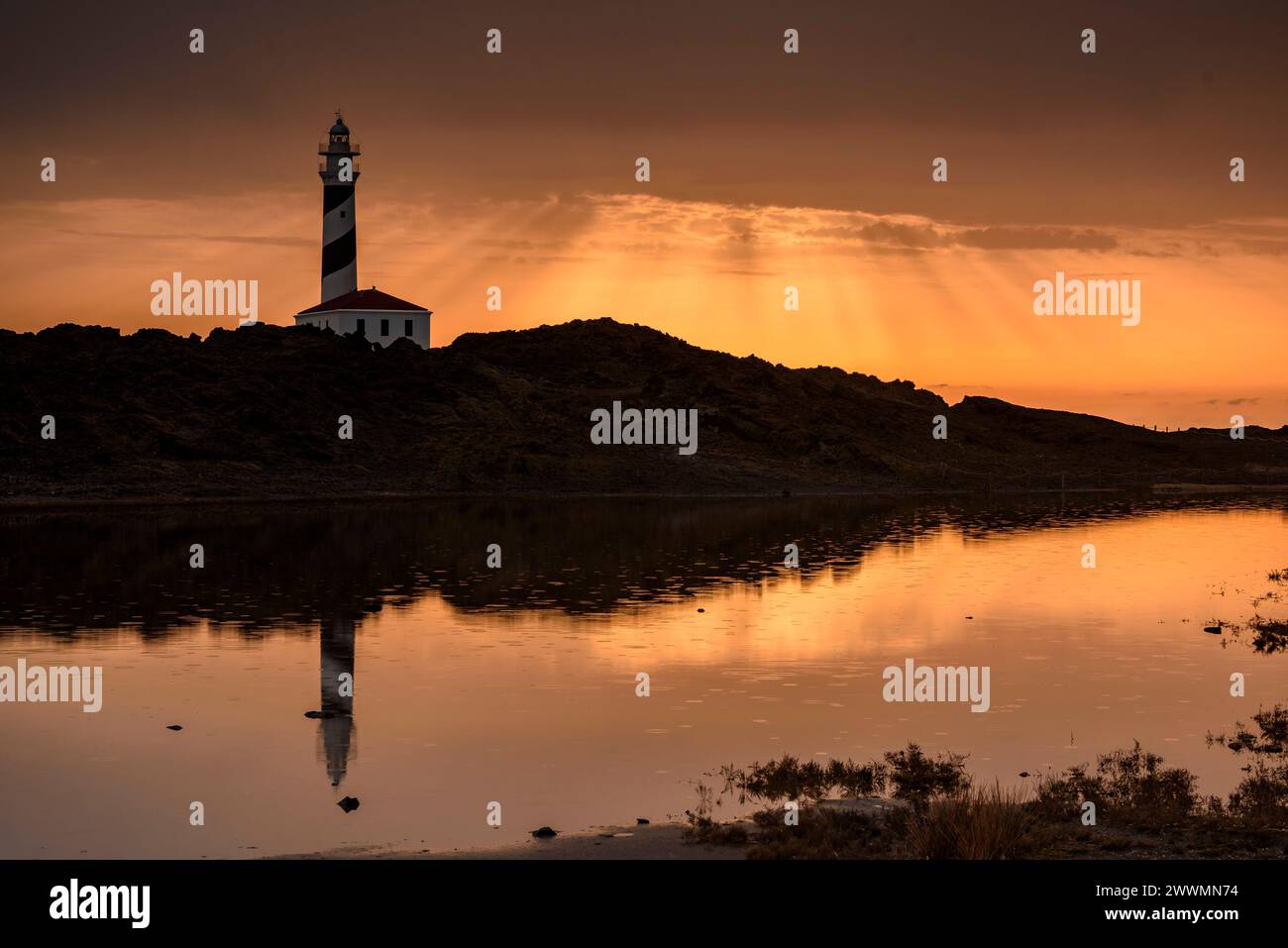 Alba al faro di Favàritx con riflessioni sullo stagno temporaneo di es Cos des Síndic (Minorca, Isole Baleari, Spagna) Foto Stock