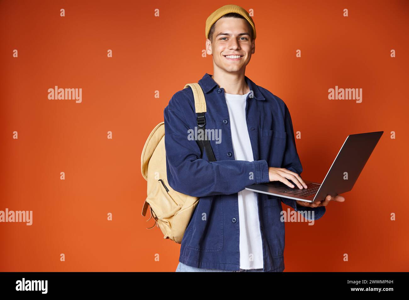 studente attraente con collegamento in rete zaino a laptop su sfondo terracotta Foto Stock