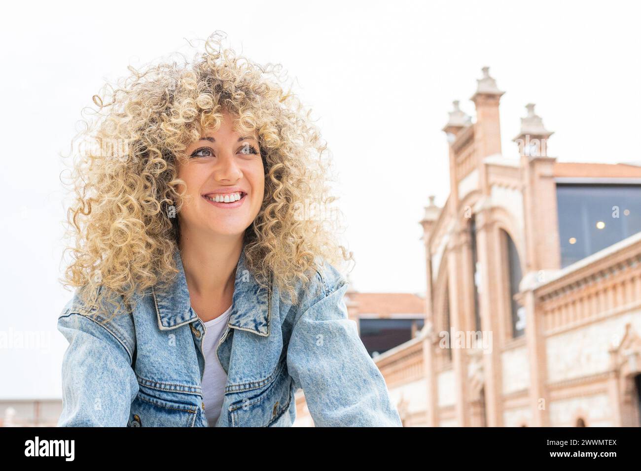 Ritratto di una giovane donna caucasica sorridente con capelli biondi ricci Foto Stock