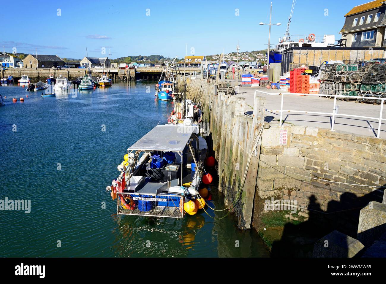 Barche ormeggiate nel porto con il cancello di chiusura e gli edifici cittadini sul retro, West Bay, Dorset, Regno Unito, Europa. Foto Stock