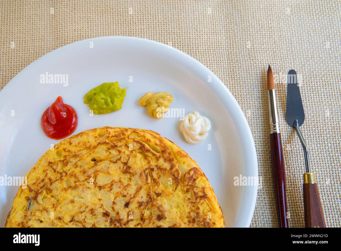 Cucina artistica: Omelette spagnole e tavolozza di salse assortite, servite con pennello e coltello. Foto Stock