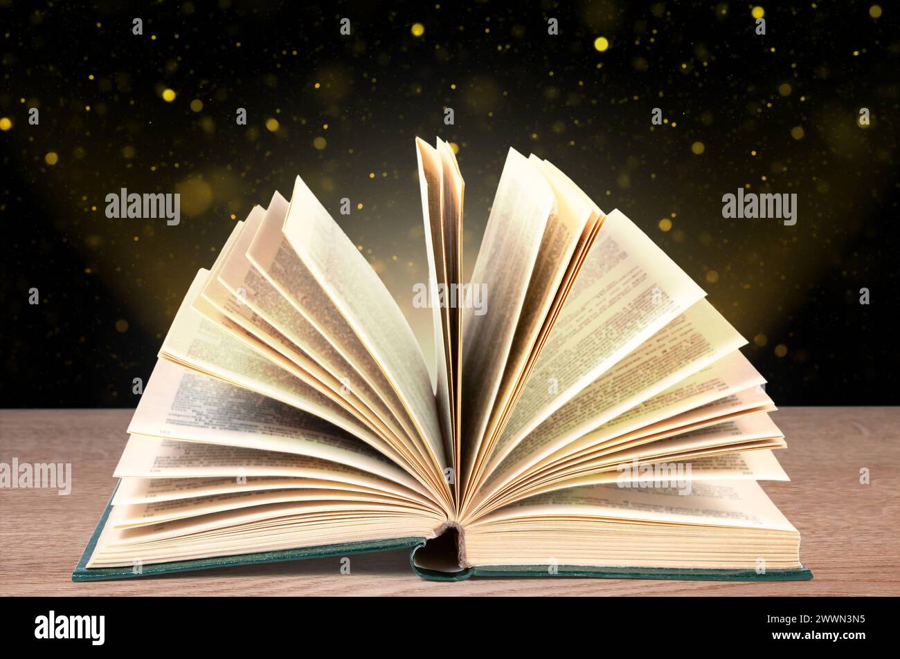 Libro pieghevole su una superficie di legno su sfondo scuro con bokeh. Foto Stock