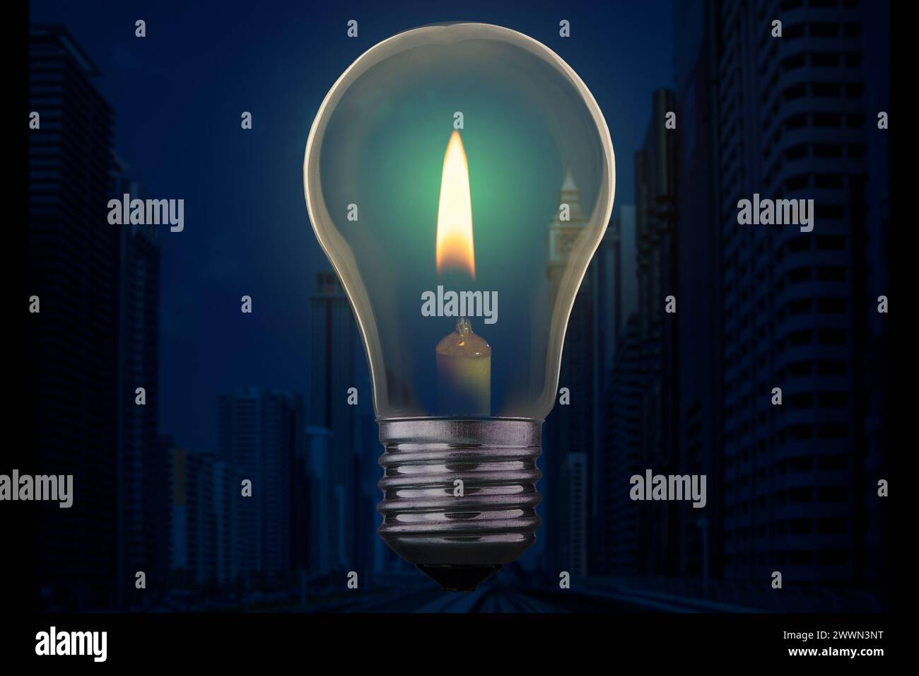 Lampadina con candele che bruciano all'interno contro un moderno quartiere cittadino senza elettricità di notte. Concetto di blackout di emergenza. Foto Stock