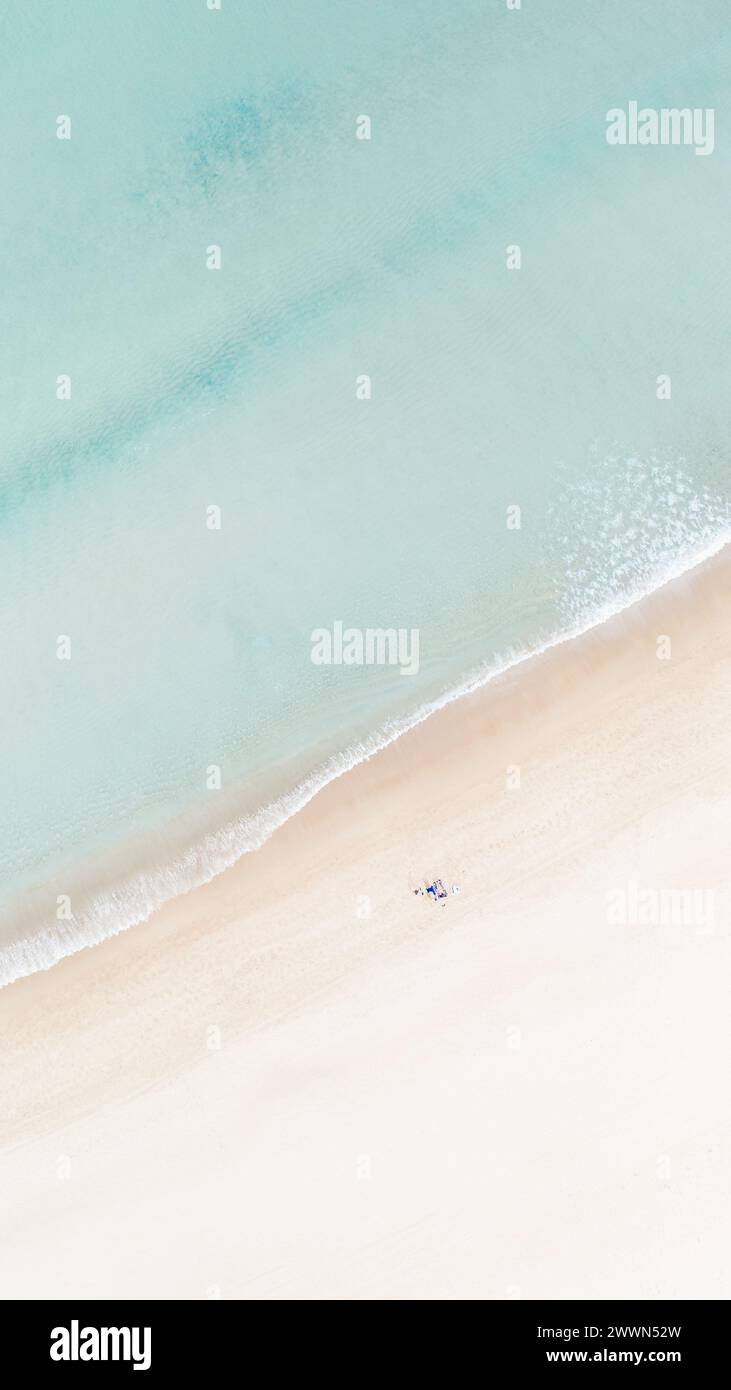 Vista verticale aerea della spiaggia pastello con onde serene e atmosfera rilassante - perfetto per fughe costiere e vacanze di relax Foto Stock