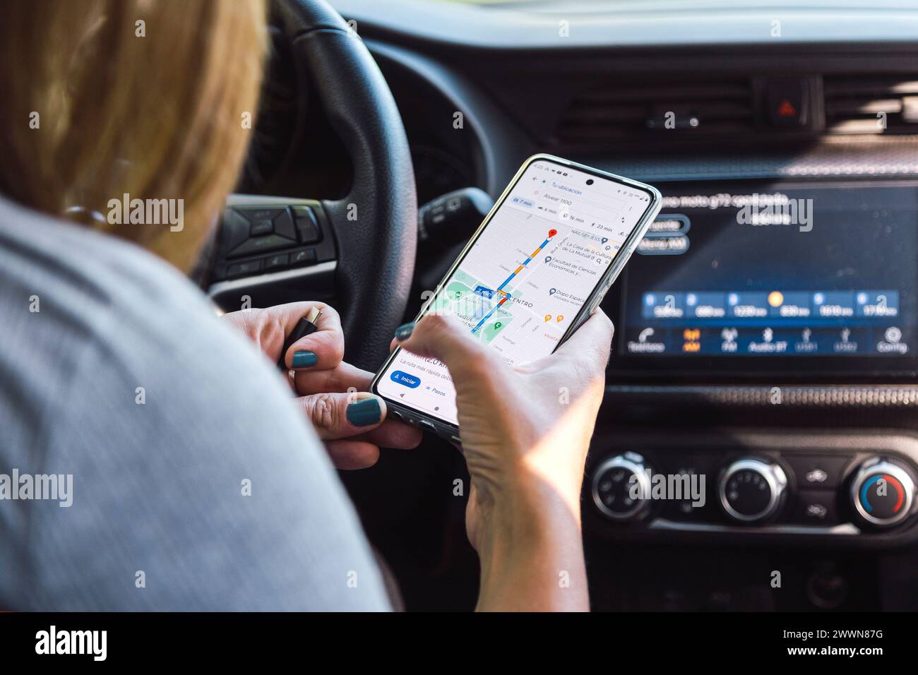 Donna in auto che usa Google Maps nel suo cellulare. Ricerca di un percorso nell'app GPS. ROSARIO, ARGENTINA - 22 MARZO 2024. Foto Stock