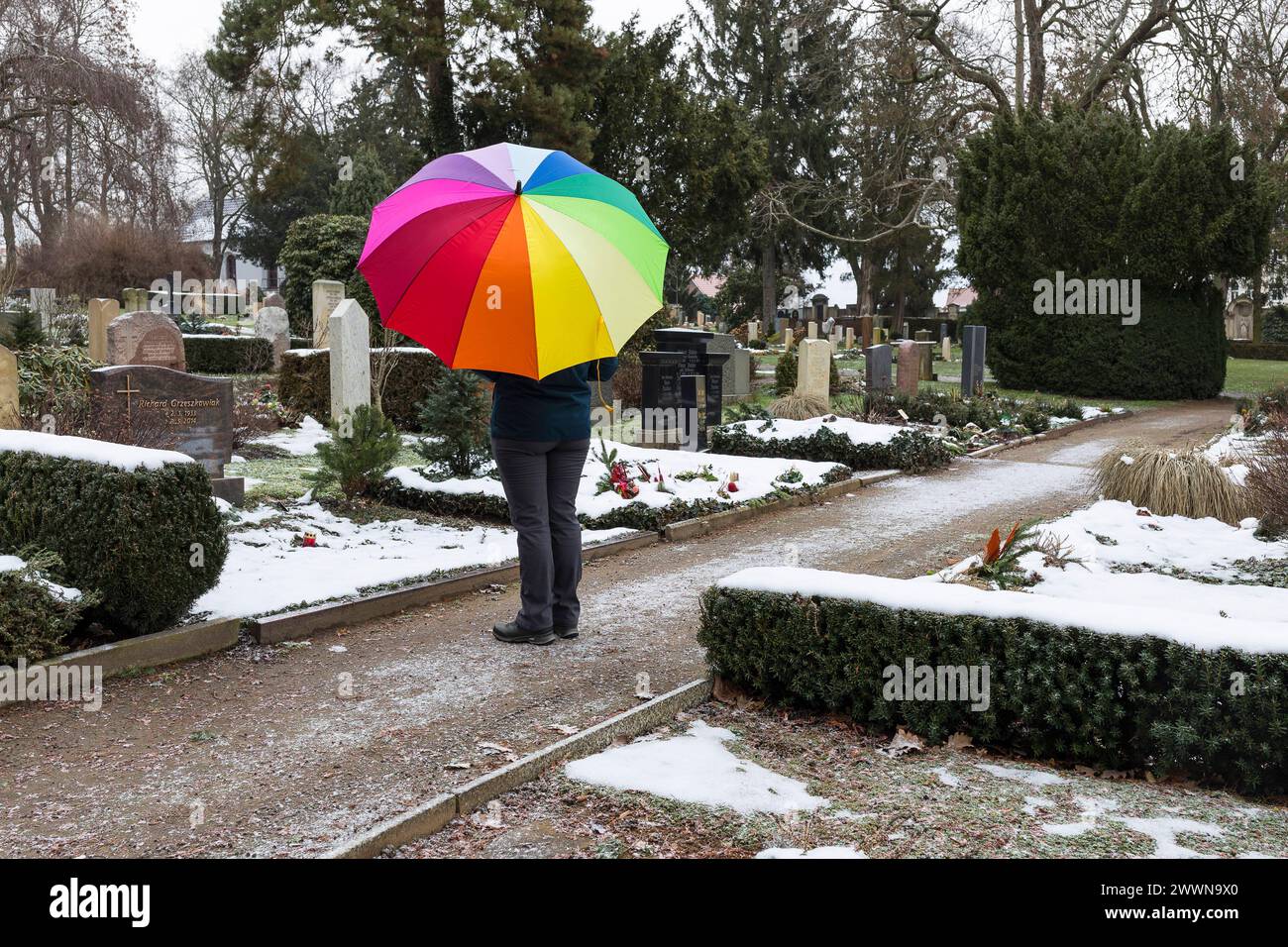 Mensch mit buntem Regenschirm bei grauem Wetter vor einem Grab, Friedhof Riesa, Sachsen, Deutschland *** uomo con un ombrello colorato davanti a un gr Foto Stock