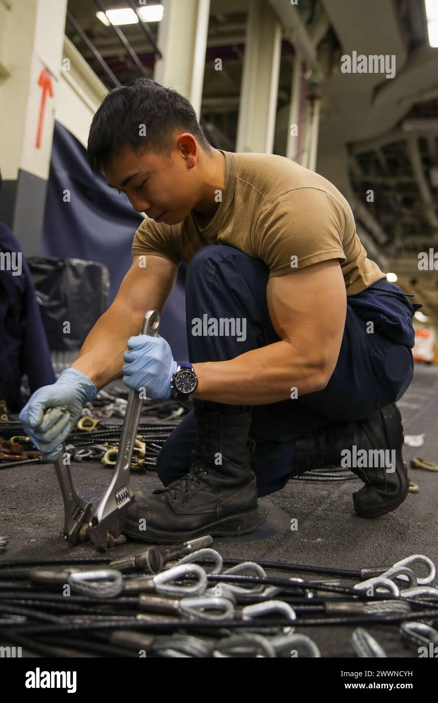 240212-N-VR794-1069 SAN DIEGO (12 febbraio 2024) – Boatswain's Mate 3rd Class Steven Ko, di Seattle, smonta catene per il rinnovo nell'area di stivaggio dei veicoli a bordo della portaerei d'assalto anfibio USS Tripoli (LHA 7), 12 febbraio. Tripoli è una nave d'assalto anfibia di classe americana portata a San Diego. Marina Foto Stock