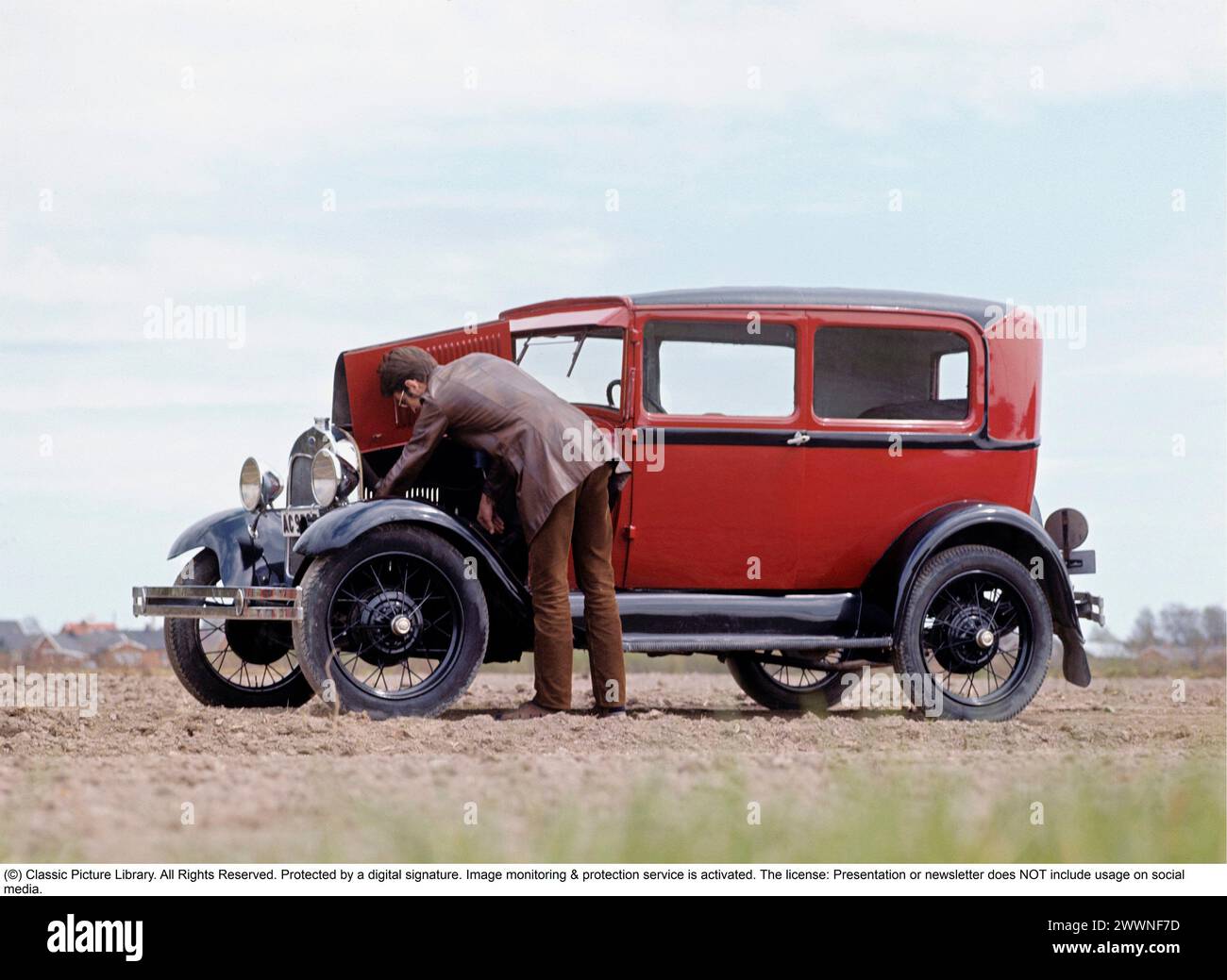 La vecchia macchina. Un uomo che guarda qualcosa nel motore della sua auto, una Ford Model A 1930. Foto Stock