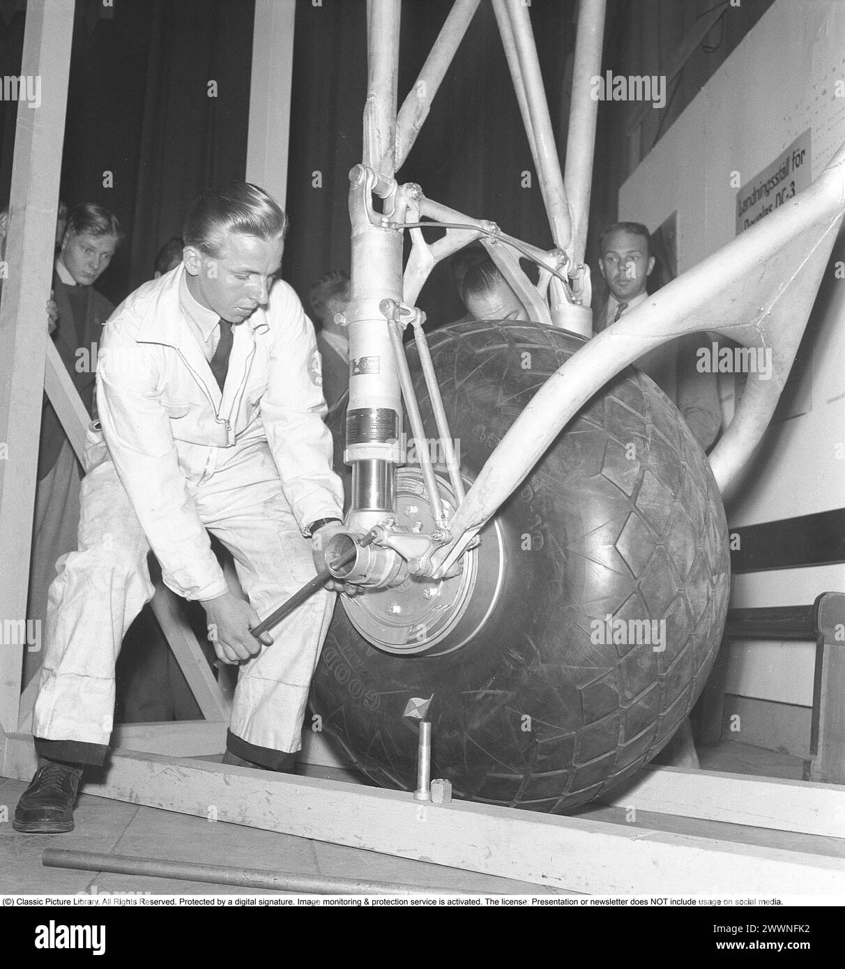 Pneumatico grande negli anni '1940 Giovane meccanico su uno pneumatico e carrello di atterraggio di un aereo Douglas DC3. 1943. Kristoffersson rif. F22-1 Foto Stock