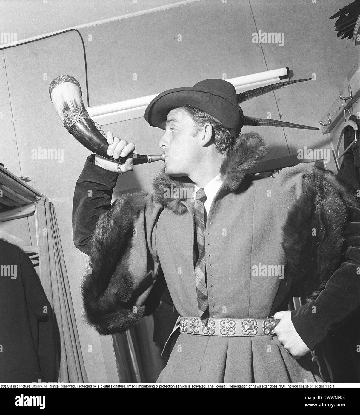Al teatro negli anni '1940 Un giovane di un gruppo teatrale è in piedi nel suo spogliatoio provando il suo costume da palco e soffiando il corno che accompagna il costume. 1949 Kristoffersson rif. AP73-5 Foto Stock