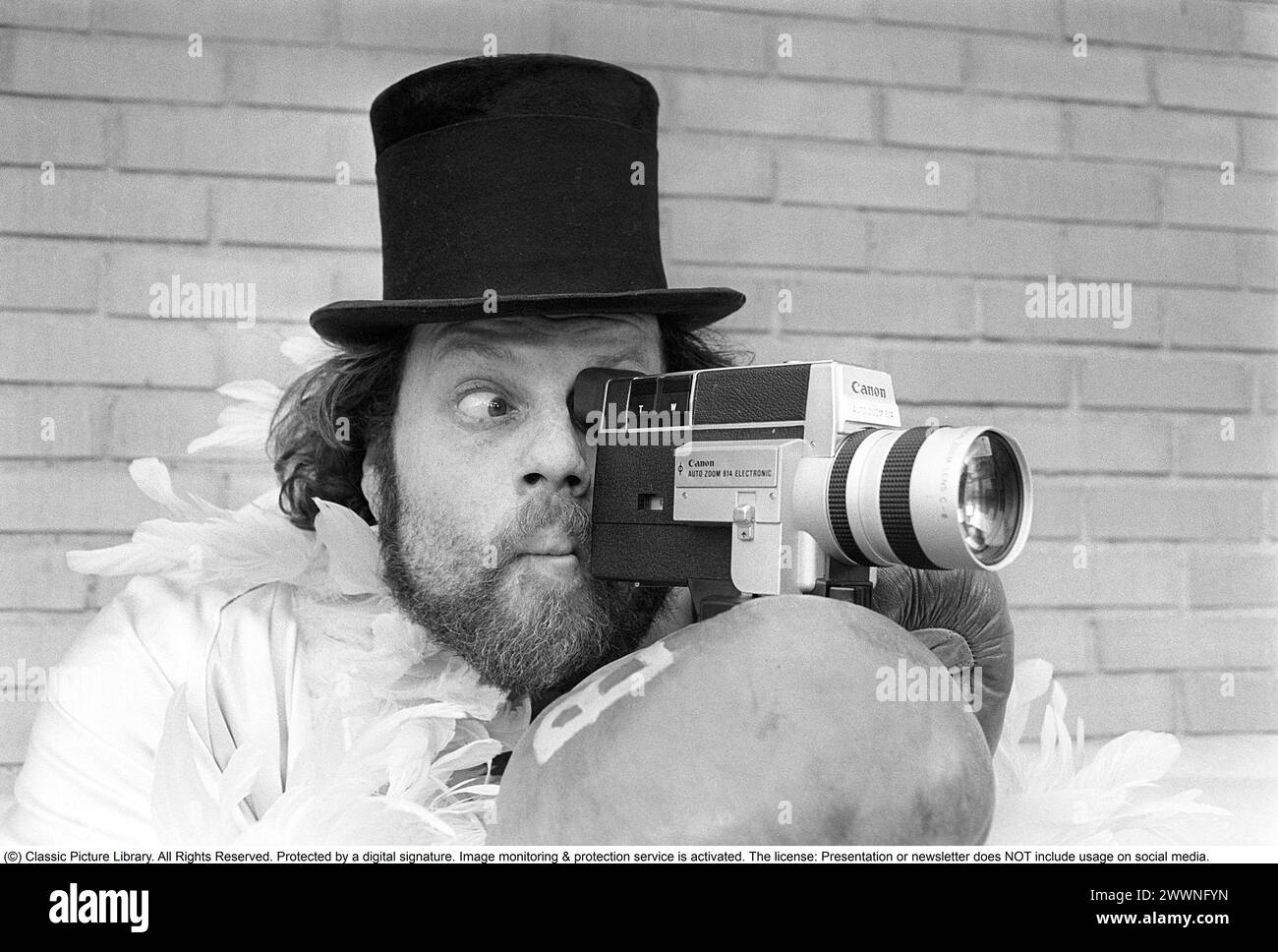 Negli anni '1970 Un uomo sta filmando con una macchina fotografica amatoriale. Il film è stato poi sviluppato e mostrato su un proiettore cinematografico su uno schermo pieghevole a casa. Ricky Bruch (1946-2011) atleta svedese di atletica leggera. Era noto per essere un po' uno showman qui raffigurato con guanti da boxe, una boa di piume e un cappello cilindrico. 1975 Foto Stock