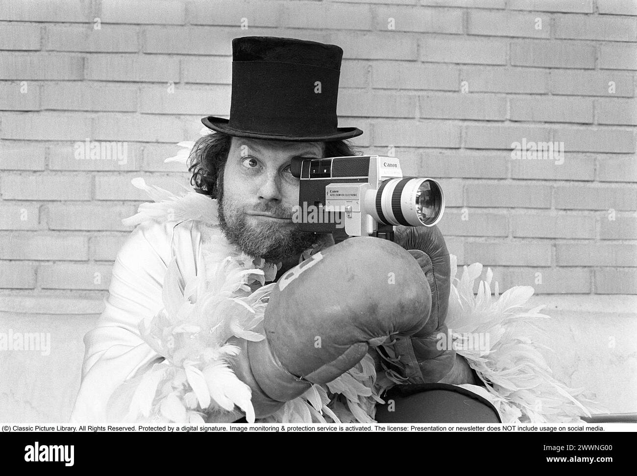 Negli anni '1970 Un uomo sta filmando con una macchina fotografica amatoriale. Il film è stato poi sviluppato e mostrato su un proiettore cinematografico su uno schermo pieghevole a casa. Ricky Bruch (1946-2011) atleta svedese di atletica leggera. Era noto per essere un po' uno showman qui raffigurato con guanti da boxe, una boa di piume e un cappello cilindrico. 1975 Foto Stock