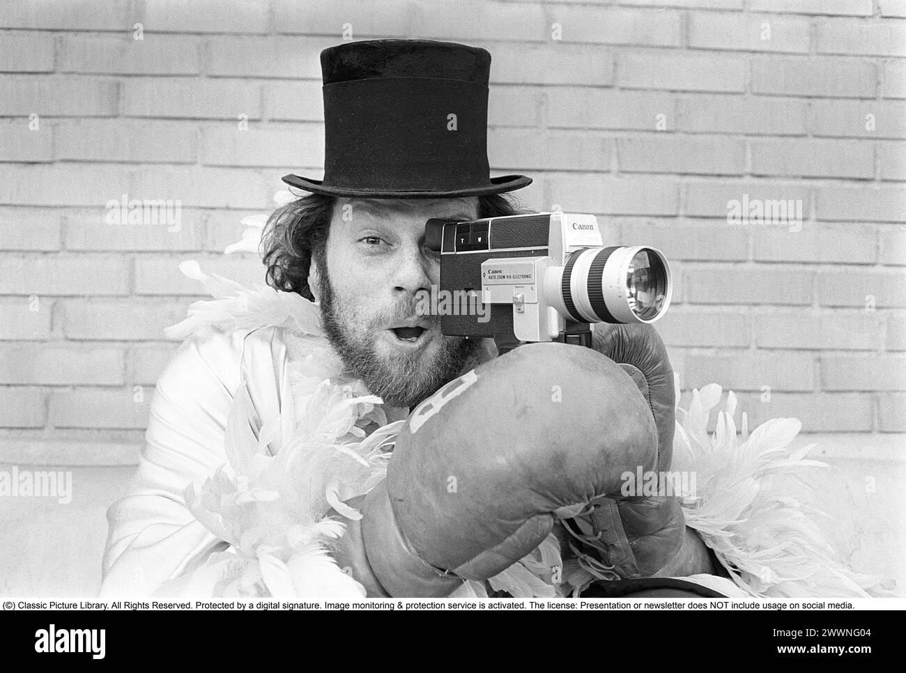 Negli anni '1970 Un uomo sta filmando con una macchina fotografica amatoriale. Il film è stato poi sviluppato e mostrato su un proiettore cinematografico su uno schermo pieghevole a casa. Ricky Bruch (1946-2011) atleta svedese di atletica leggera. Era noto per essere un po' uno showman qui raffigurato con guanti da boxe, una boa di piume e un cappello cilindrico. 1975 Foto Stock