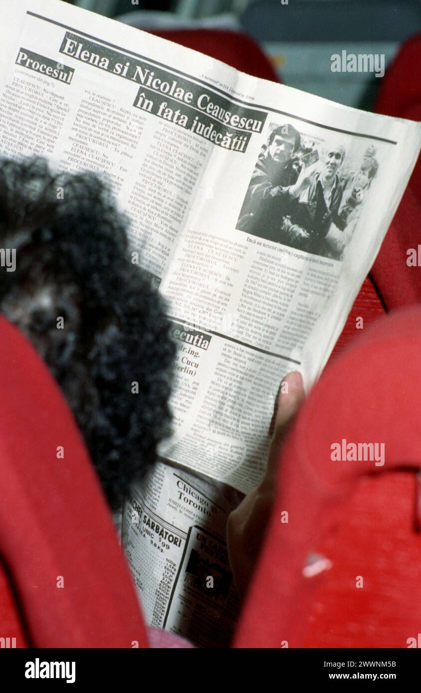 Un paio di settimane dopo la rivoluzione rumena del dicembre 1989, un passeggero su un aereo TAROM in volo per Bucarest legge un giornale sugli eventi in Romania. La maggior parte dei passeggeri erano cittadini di origine rumena che lasciarono il paese durante il comunismo. Foto Stock