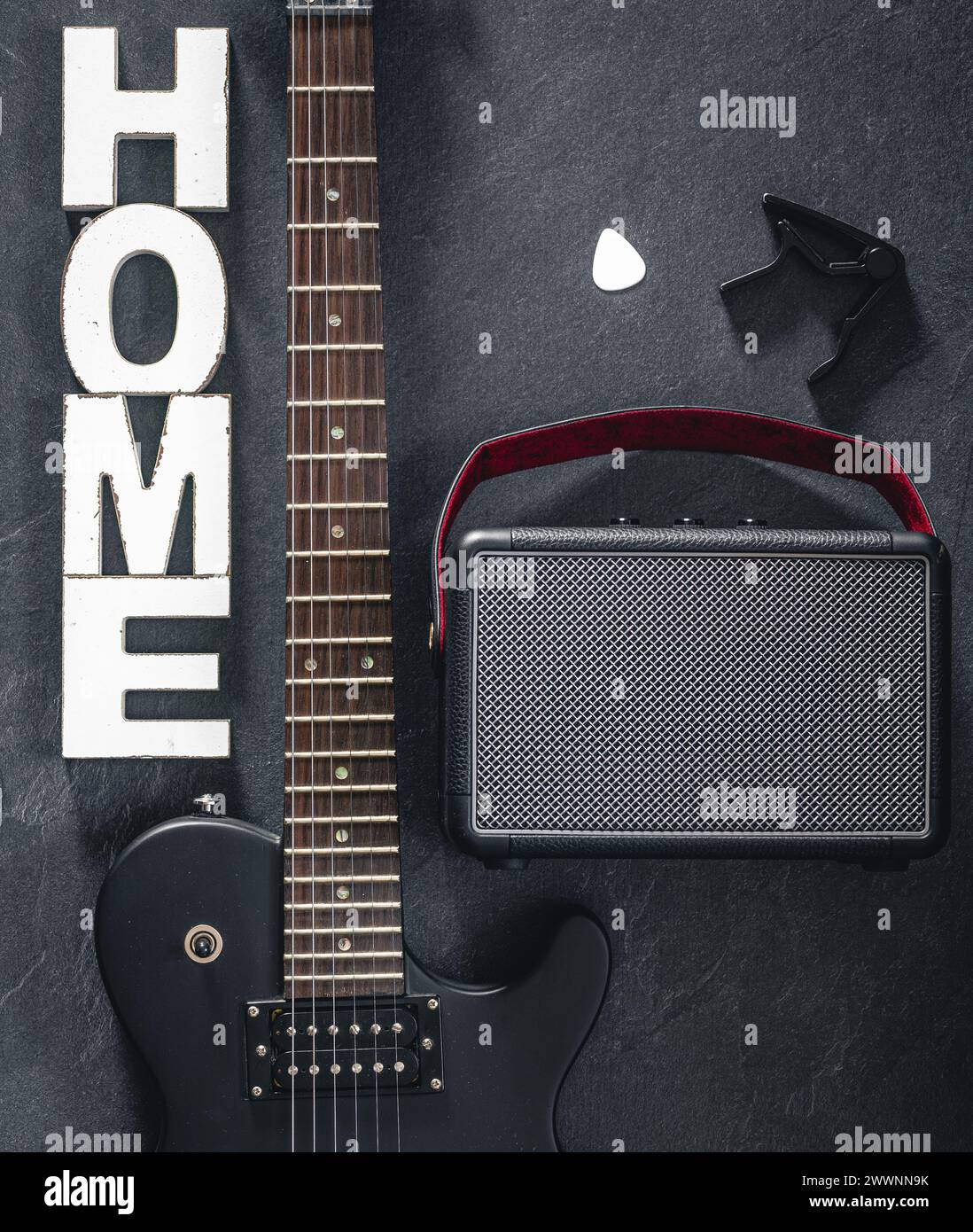 Chitarra elettrica e amplificatore su sfondo scuro con la parola decorativa Home. Foto Stock