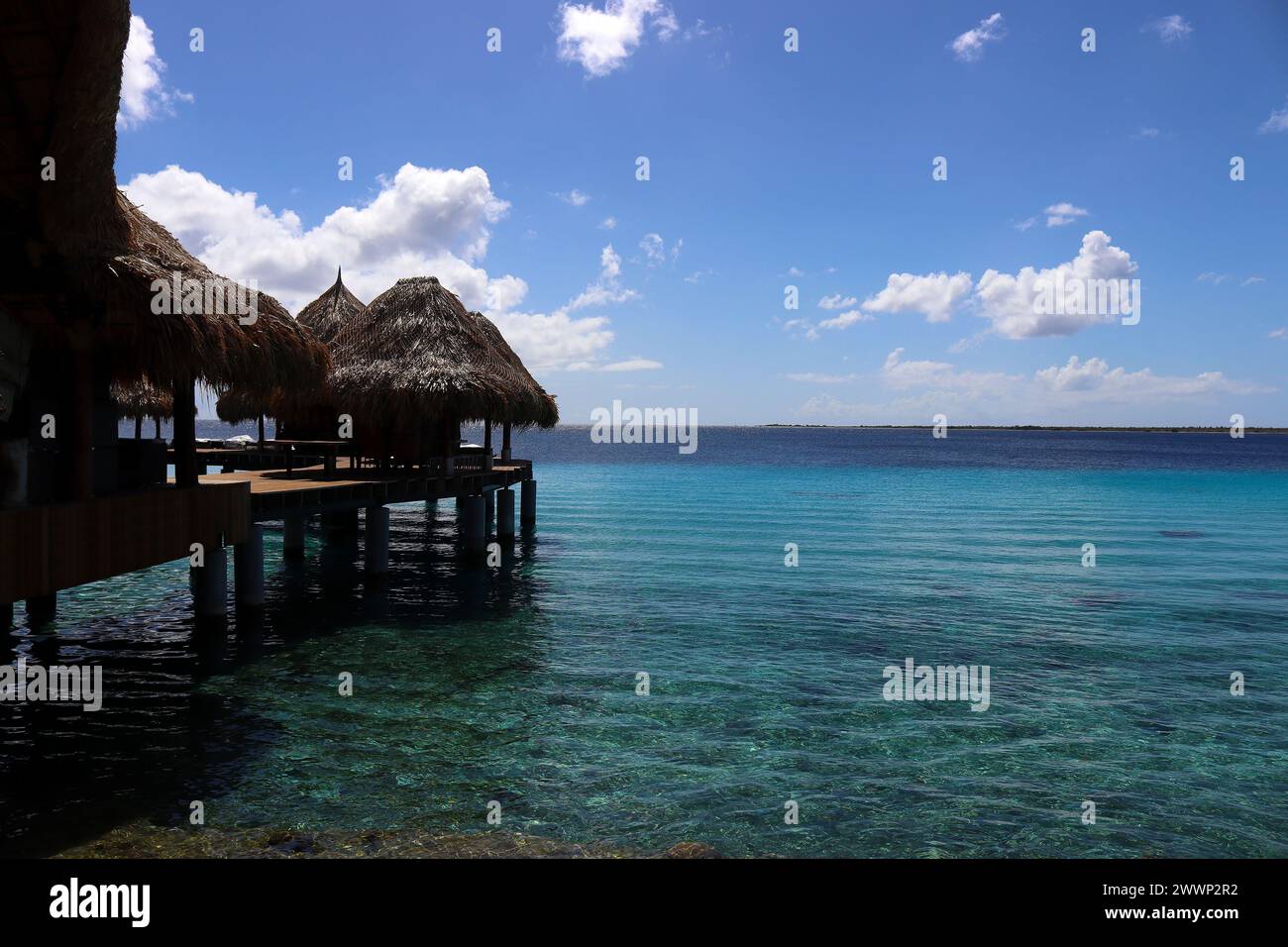 Vibrazioni caraibiche - capanne di paglia su palafitte in acque turchesi, isola Bonaire, Paesi Bassi caraibici Foto Stock