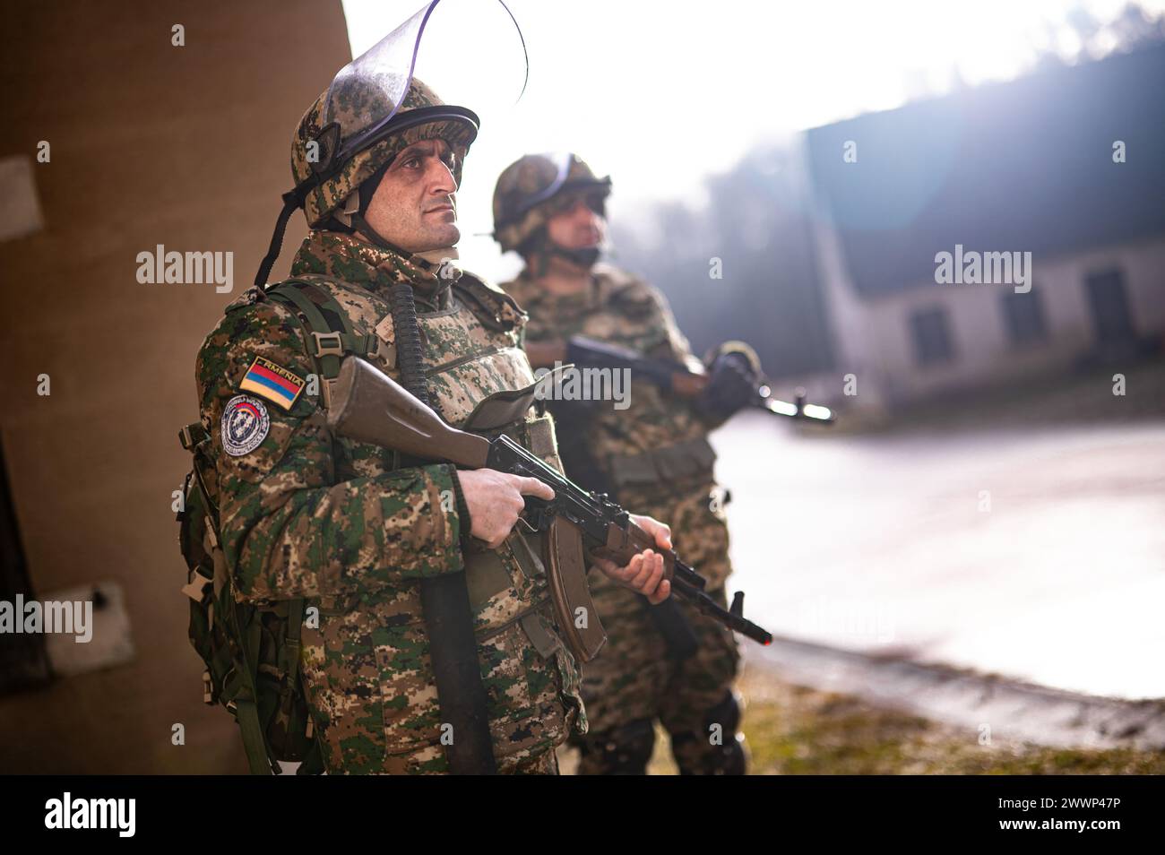 I soldati armeni guardano una rivolta simulata crescere durante l'addestramento per il controllo della sommossa della folla durante l'addestramento per il controllo della sommossa della folla durante le forze del Kosovo 33 (KFOR 33) esercitazione di prova della missione (MRE) nella Hohenfels Training area, Germania, 10 febbraio 2024. KFOR 33 MRE è un evento di formazione multinazionale condotto per preparare il 48° IBCT (GA ARNG) e i partner multinazionali per il loro dispiegamento al comando regionale del Kosovo Est. Esercito Foto Stock