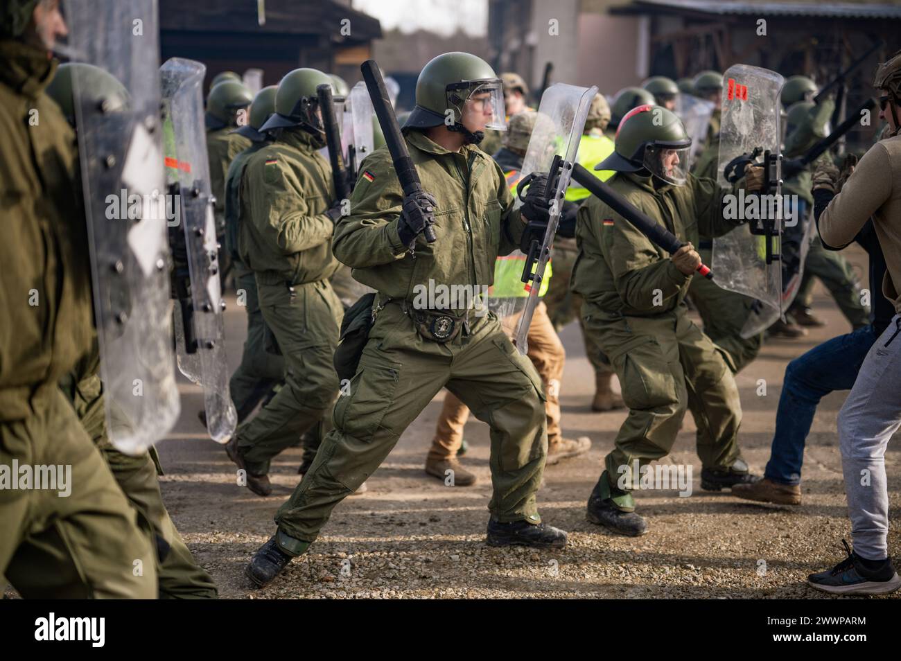 I soldati tedeschi colpiscono i rivoltosi simulati durante l'addestramento di controllo della folla durante le forze del Kosovo 33 (KFOR 33) esercitazione di prova della missione (MRE) nell'area di addestramento di Hohenfels, Germania, 10 febbraio 2024. KFOR 33 MRE è un evento di formazione multinazionale condotto per preparare il 48° IBCT (GA ARNG) e i partner multinazionali per il loro dispiegamento al comando regionale del Kosovo Est. Esercito Foto Stock