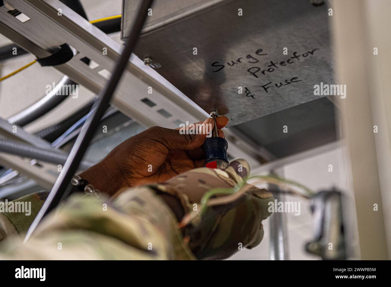 Un Airman della U.S. Air Force fissa un pannello in una scatola di alimentazione all'interno del sito del ricevitore del trasmettitore terra-aria presso la Moody Air Force base, Georgia, 21 febbraio 2024. Per aggiornare correttamente le radio, Airmen ha completato il progetto in varie fasi. La prima fase della modernizzazione delle radio richiedeva aggiornamenti alle linee di trasmissione. Aeronautica militare Foto Stock