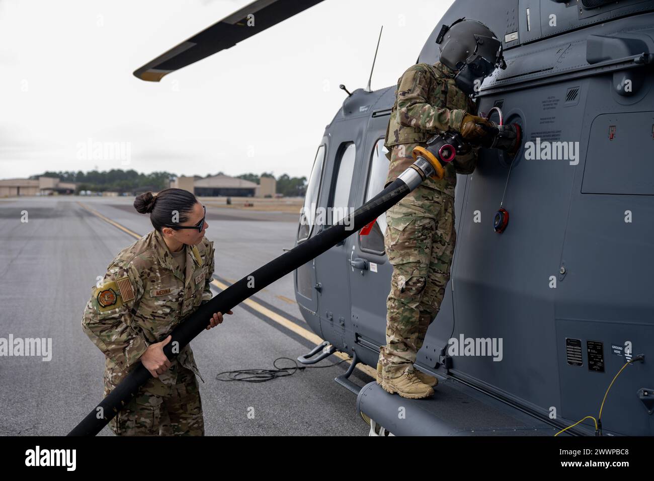 U.S. Air Force Tech. Sergente David Rasmussen, a destra, Global Strike MH-139A Grey Wolf, ingegnere di volo del programma di test per elicotteri, e sergente Michelle Medina, 1st Special Operations Logistics Readiness Squadron Fuels Mobile Distribution Supervisor, eseguono una prova di concetto prima di un test di rifornimento a caldo presso Hurlburt Field, Florida, 9 febbraio 2024. Questo è il primo test di rifornimento di gas caldo del Dipartimento della difesa sul nuovo MH-139A, che sta sostituendo l'elicottero UH-1N Huey: Un rifornimento di carburante a caldo implica il rifornimento di un aereo con i motori ancora in funzione, riducendo i tempi di risposta e mantenendo l'aereo in funzione Foto Stock