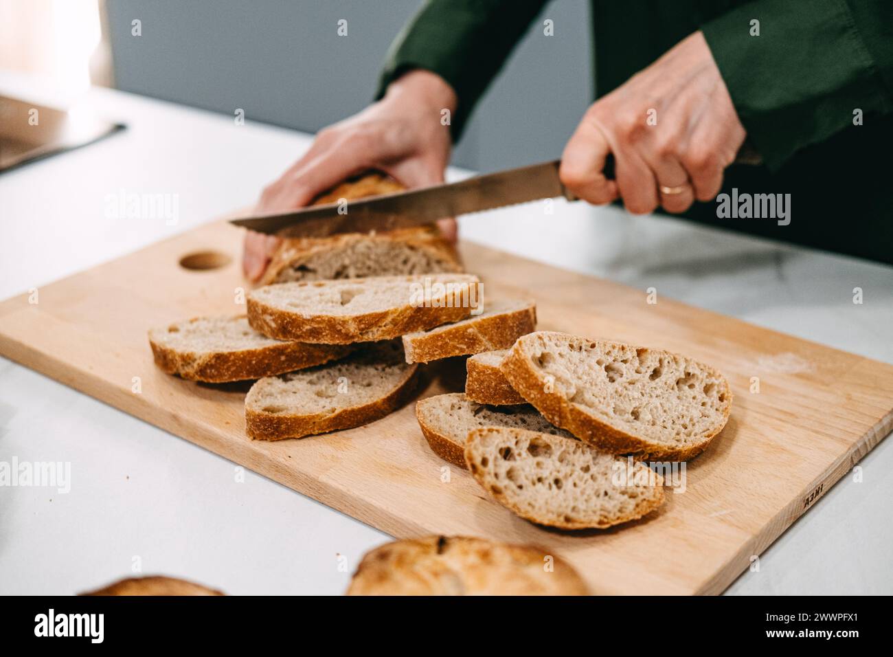 Persona che affetta il pane artigianale sul tagliere. Pane artigianale fatto in casa privo di additivi e conservanti Foto Stock