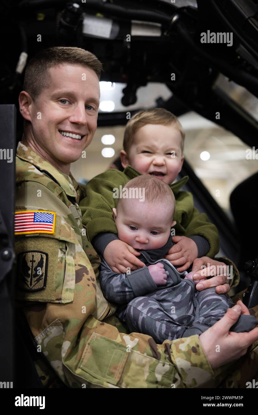 Il capitano Matthew Chasin, comandante dell'A Co. 1/126th Aviation Regiment e pilota DELL'UH-60 Black Hawk, tiene i suoi due figli all'interno di un UH-60, 17 febbraio 2024, presso la Quonset Air National Guard base, North Kingstown, RI. Chasin è tornato da uno schieramento di 10 mesi in Kosovo schierato a sostegno dell'operazione Joint Guardian, una missione di mantenimento della pace della NATO sotto la Kosovo Force (KFOR). Guardia Nazionale dell'esercito Foto Stock