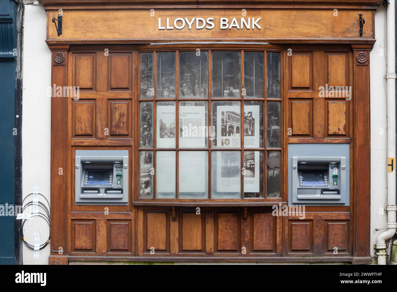 Due sportelli automatici o bancomat fuori da una banca Lloyds a Winchester, Inghilterra. Cornice per finestre in legno con esposizione storica. Marzo 2024. Foto Stock