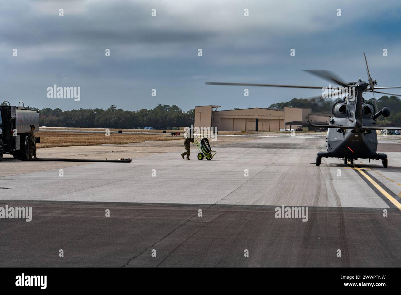 U.S. Air Force Tech. Il sergente David Rasmussen, Global Strike Command MH-139A Grey Wolf, ingegnere di volo del programma di test per elicotteri, spinge l'estintore verso l'elicottero durante un test di rifornimento a caldo presso Hurlburt Field, Florida, 9 febbraio 2024. Questo è il primo test di rifornimento di gas caldo del Dipartimento della difesa sul nuovo MH-139A, che sta sostituendo l'elicottero UH-1N Huey: Un rifornimento a caldo implica il rifornimento di un aereo con i motori ancora in funzione, riducendo i tempi di risposta e mantenendo gli aeromobili pronti a completare qualsiasi missione, ovunque Air Force Foto Stock