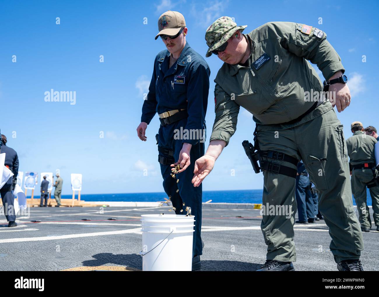 PHILIPPINE SEA (15 febbraio 2024) Electronics Technician 1st Class Levi Rush (destra), nativo di Carthage, Missouri, assegnato all'Assault Craft Unit (ACU) 5, e l'insegna Brett Kaniper, nativa di Milton, Florida, gettano le carcasse di proiettili in un secchio sul ponte di volo della nave da trasporto anfibia USS Somerset (LPD 25) durante la navigazione nel Mar delle Filippine, il 15 febbraio 2024. Somerset è attualmente in corso di operazioni di routine nella 7th Fleet degli Stati Uniti con elementi della 15th Marine Expeditionary Unit. La U.S. 7th Fleet è la più grande flotta numerata della Marina degli Stati Uniti, e di routine Foto Stock