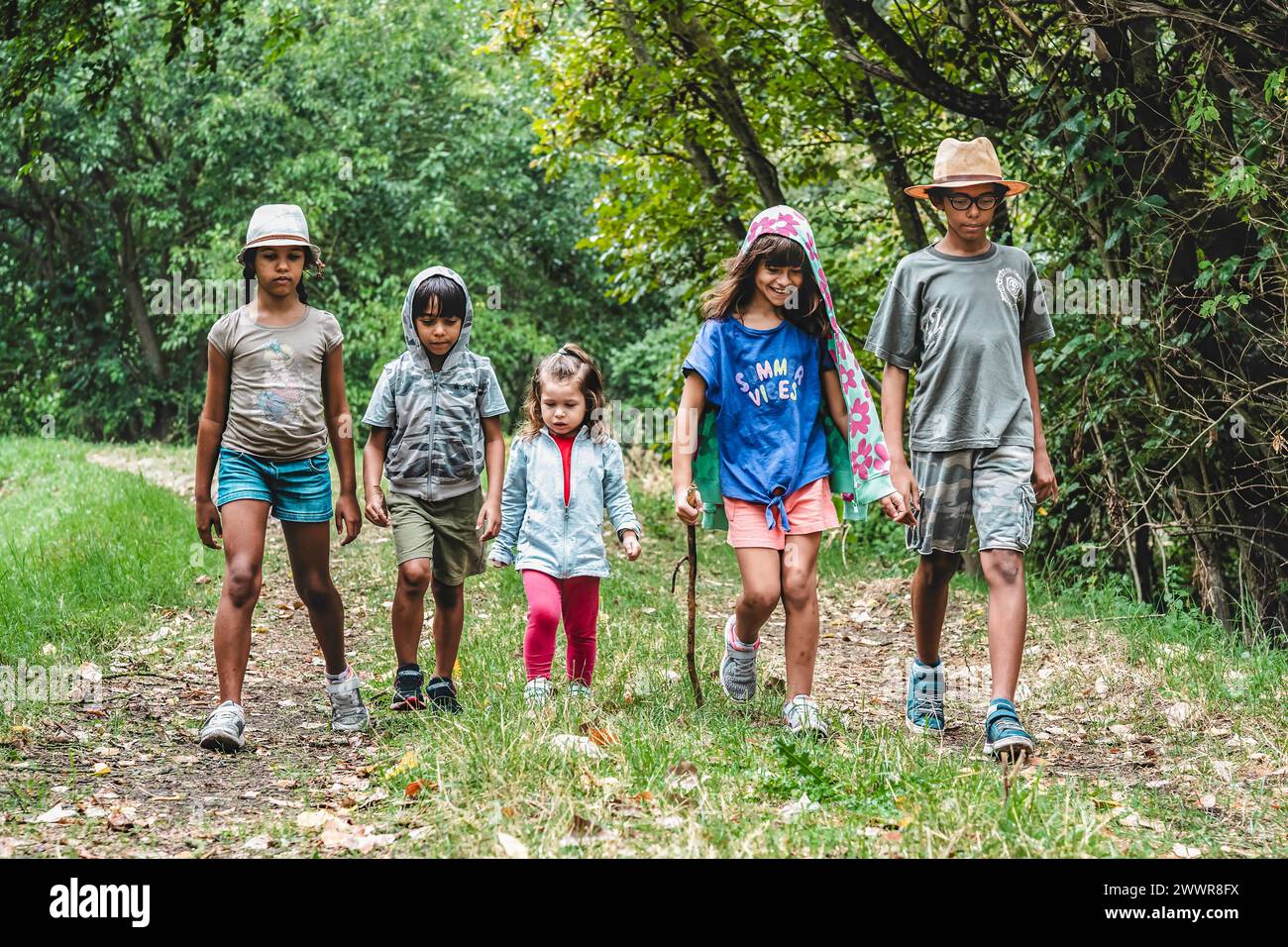 Ragazzi in viaggio nella foresta. Un gruppo diversificato marcia, abbracciando le gioie dell'infanzia e lo spirito delle avventure estive. Multietnico Foto Stock