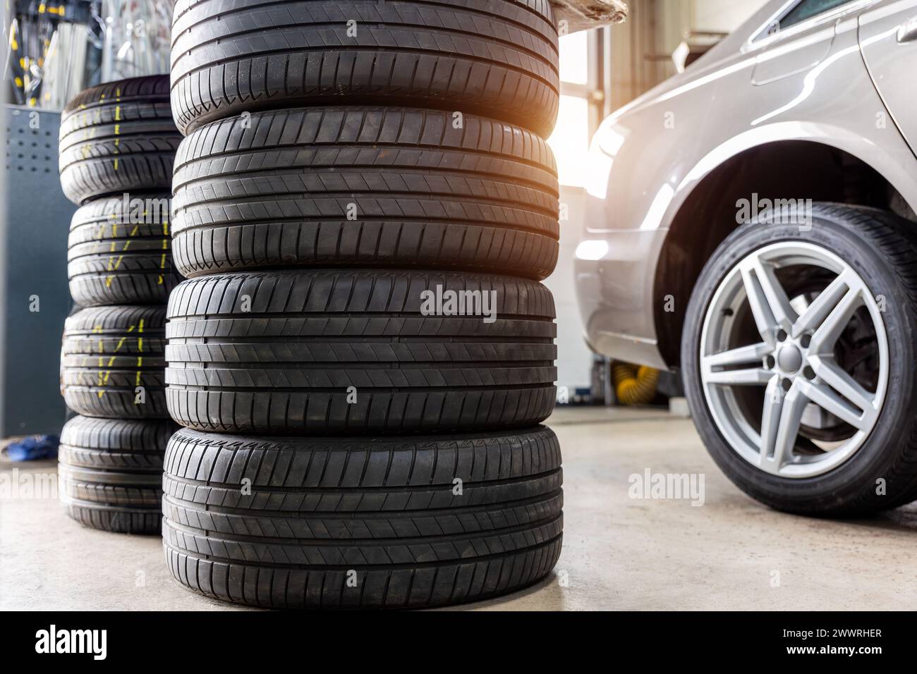 Riparazione ruote auto con vista posteriore a due sollevatori automatici. Sostituzione stagionale degli pneumatici invernali in officina. Riparazione degli pneumatici del veicolo, ispezione e manutenzione. Garage automobilistico Foto Stock