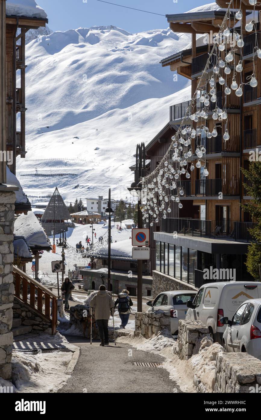 Una vista lungo la Route du Rosset nel quartiere Lac di Tignes verso il grande cono che segna la piscina Lagon, la spa e il centro ricreativo. Foto Stock