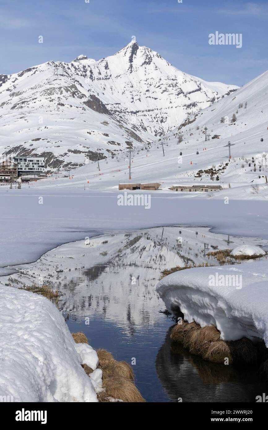 L'Aiguille de la grande Sassière nelle Alpi francesi si riflette nel Lac de Tignes, quasi completamente ghiacciato in inverno. Foto Stock