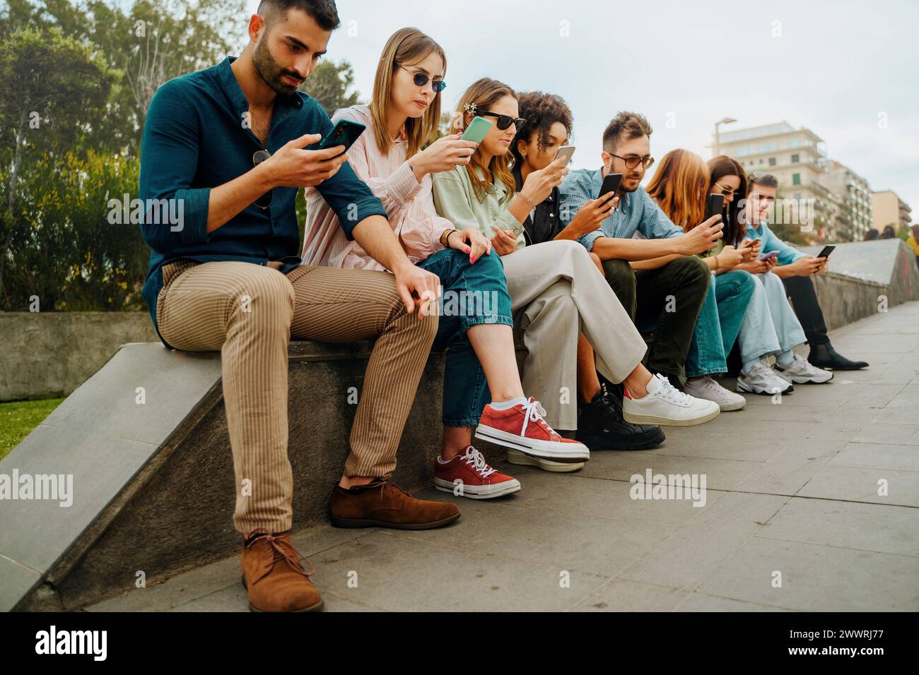 Gruppo di giovani adulti coinvolti negli smartphone - ambiente urbano, vita digitale, interazione con i social media - Millennial che si occupano di telefonare. Foto Stock