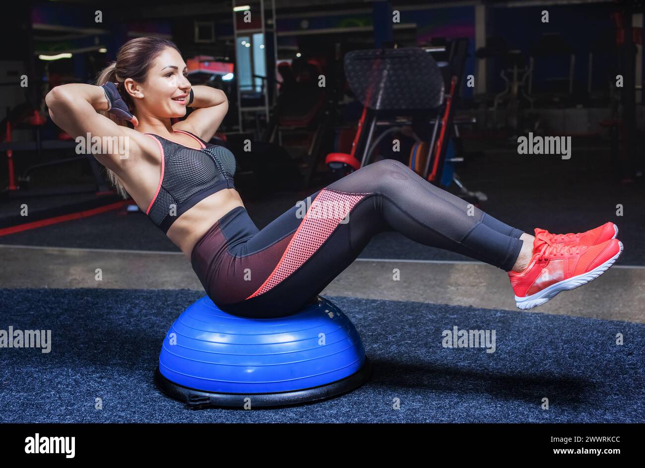 Sottile, ragazza bodybuilder, fa le esercitazioni con l'equilibrio della sfera nella palestra. Concetto sportivo, bruciore grasso e uno stile di vita sano. Foto Stock