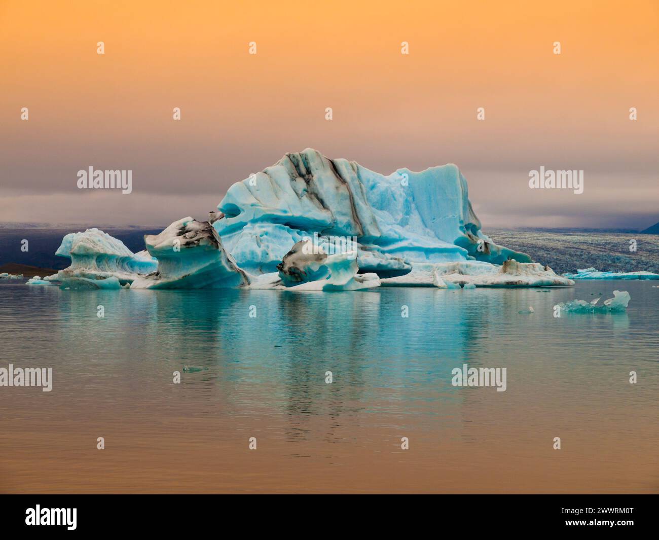 Iceberg blu nella laguna del ghiacciaio Jokulsarlon insera luce del sole rossa, Islanda Foto Stock