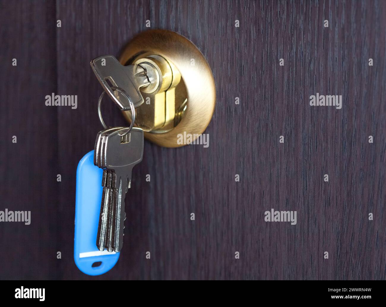 Una nuova chiave in un buco della serratura in un primo piano di una porta di legno. Foto Stock