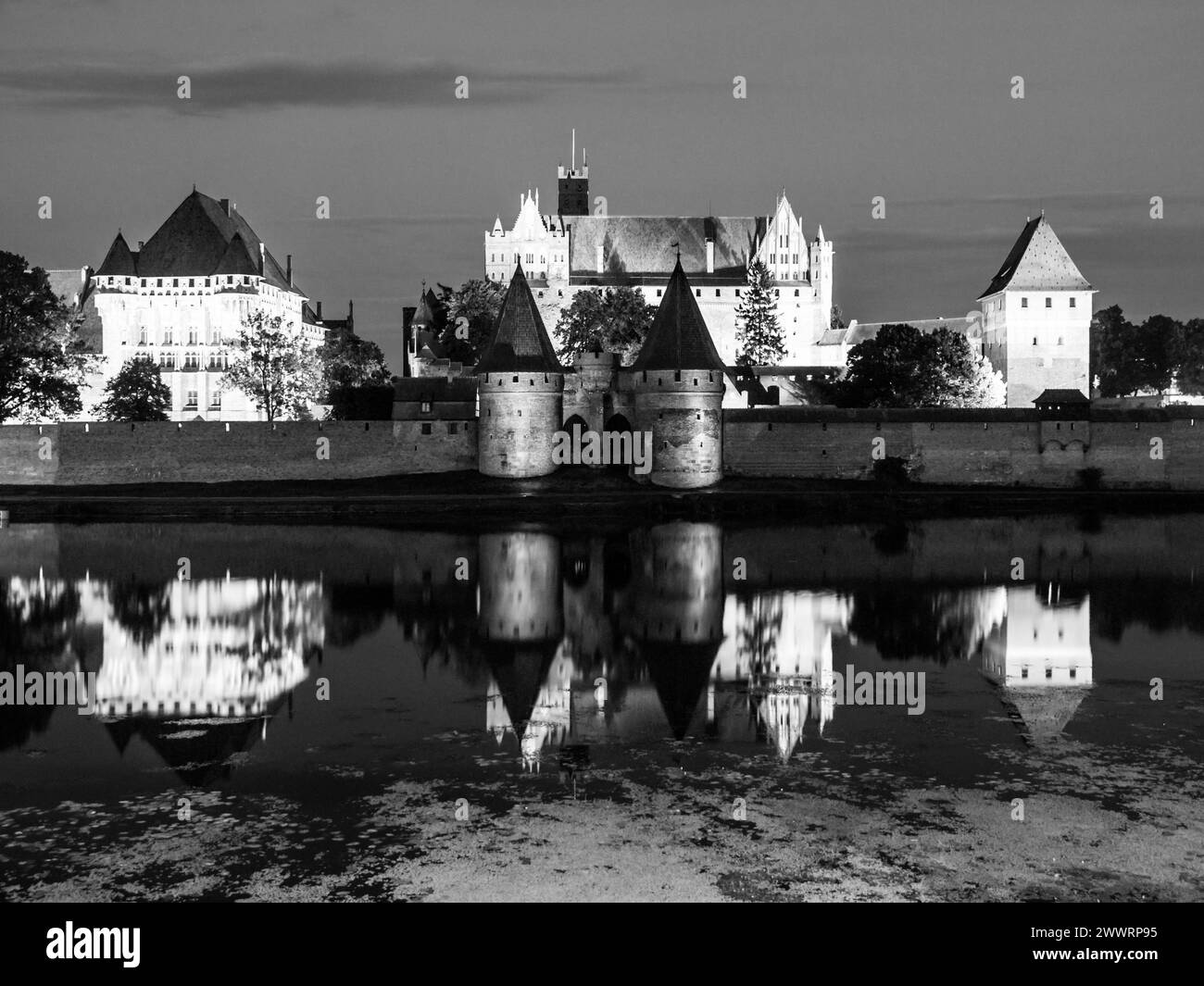 Castello di Malbork di notte con riflessione nel fiume Nogat, Polonia. Immagine in bianco e nero. Foto Stock
