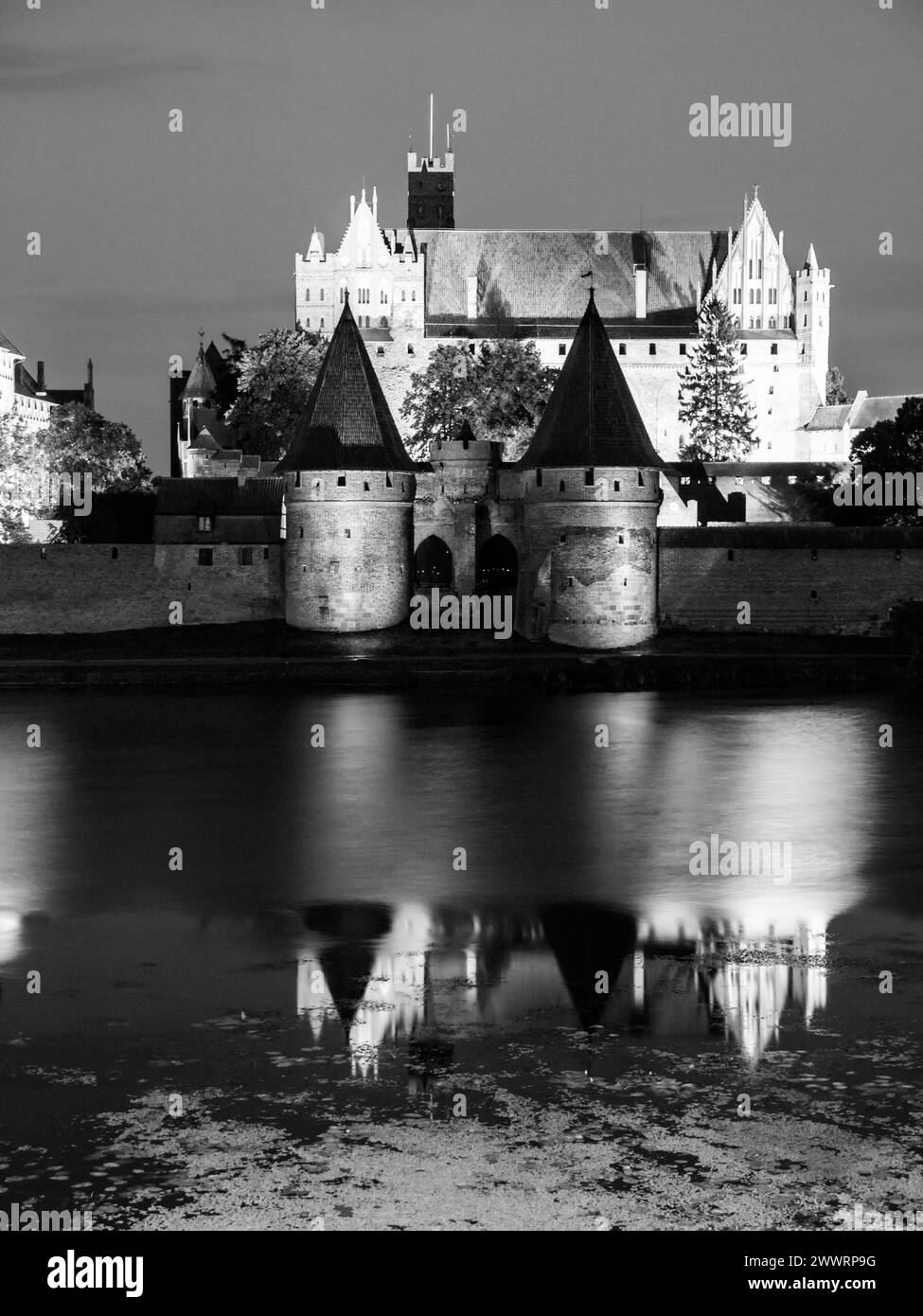 Castello di Malbork di notte con riflessione nel fiume Nogat, Polonia. Immagine in bianco e nero. Foto Stock