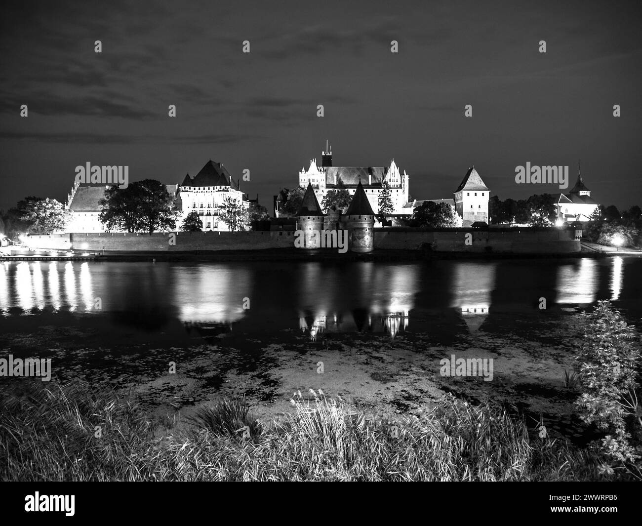 Castello di Malbork di notte con riflessione nel fiume Nogat, Polonia. Immagine in bianco e nero. Foto Stock