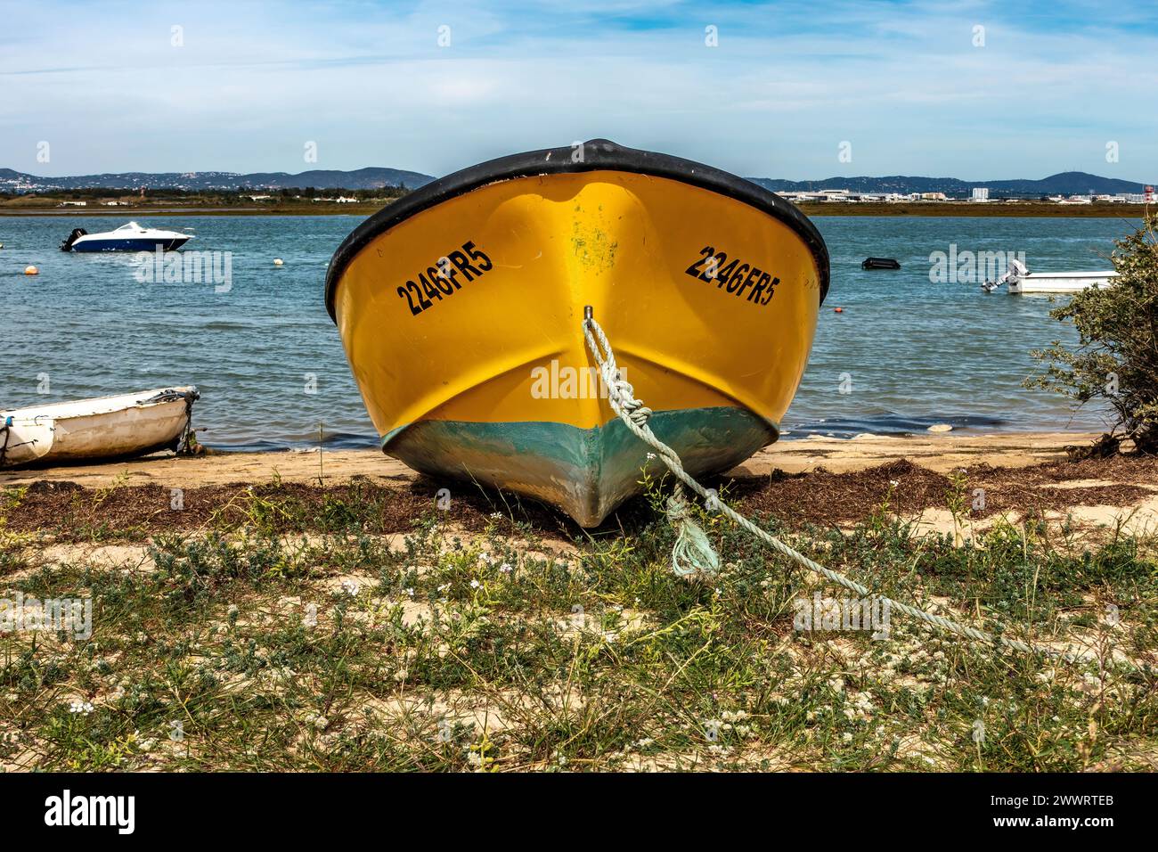 Una barca gialla luminosa ormeggiata a Praia De Faro, Portogallo. Foto Stock