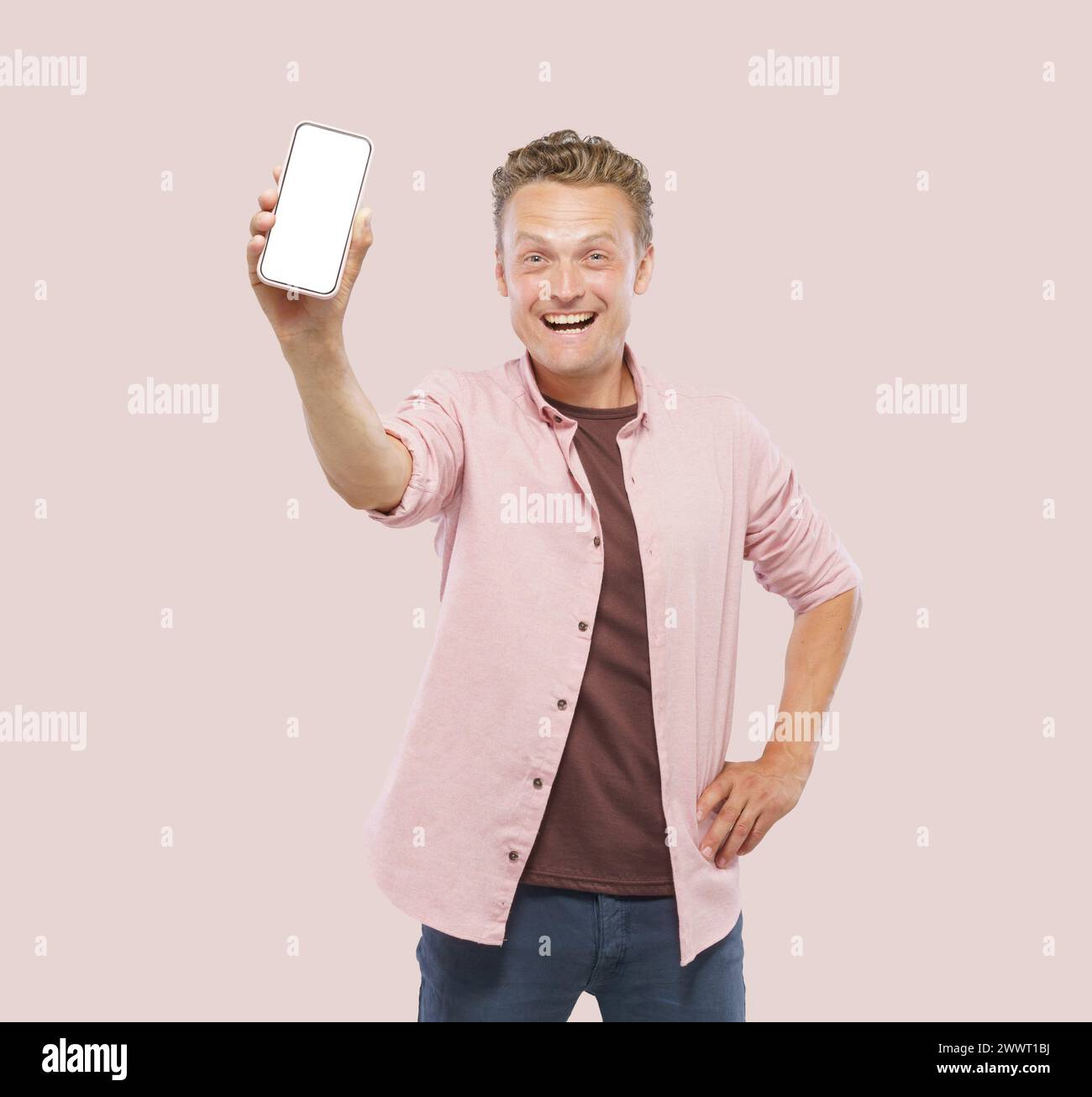 Un uomo ha in mano un cellulare bianco e sorride. Concetto di felicità ed eccitazione, come l'uomo sta potendo con il telefono, forse a Sha Foto Stock
