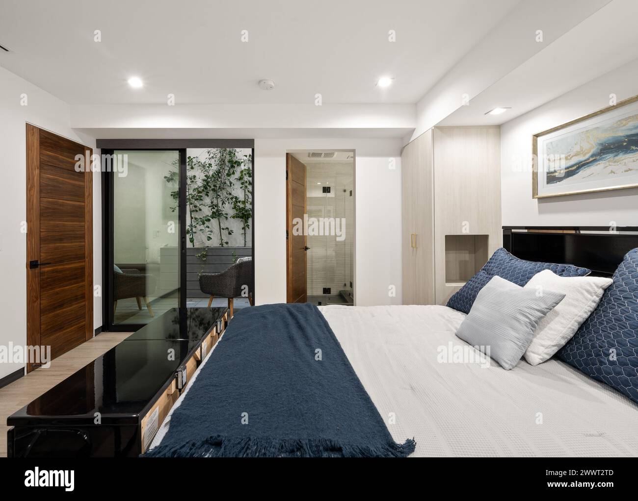 Camera dal design moderno con elegante biancheria da letto blu e bianca Foto Stock