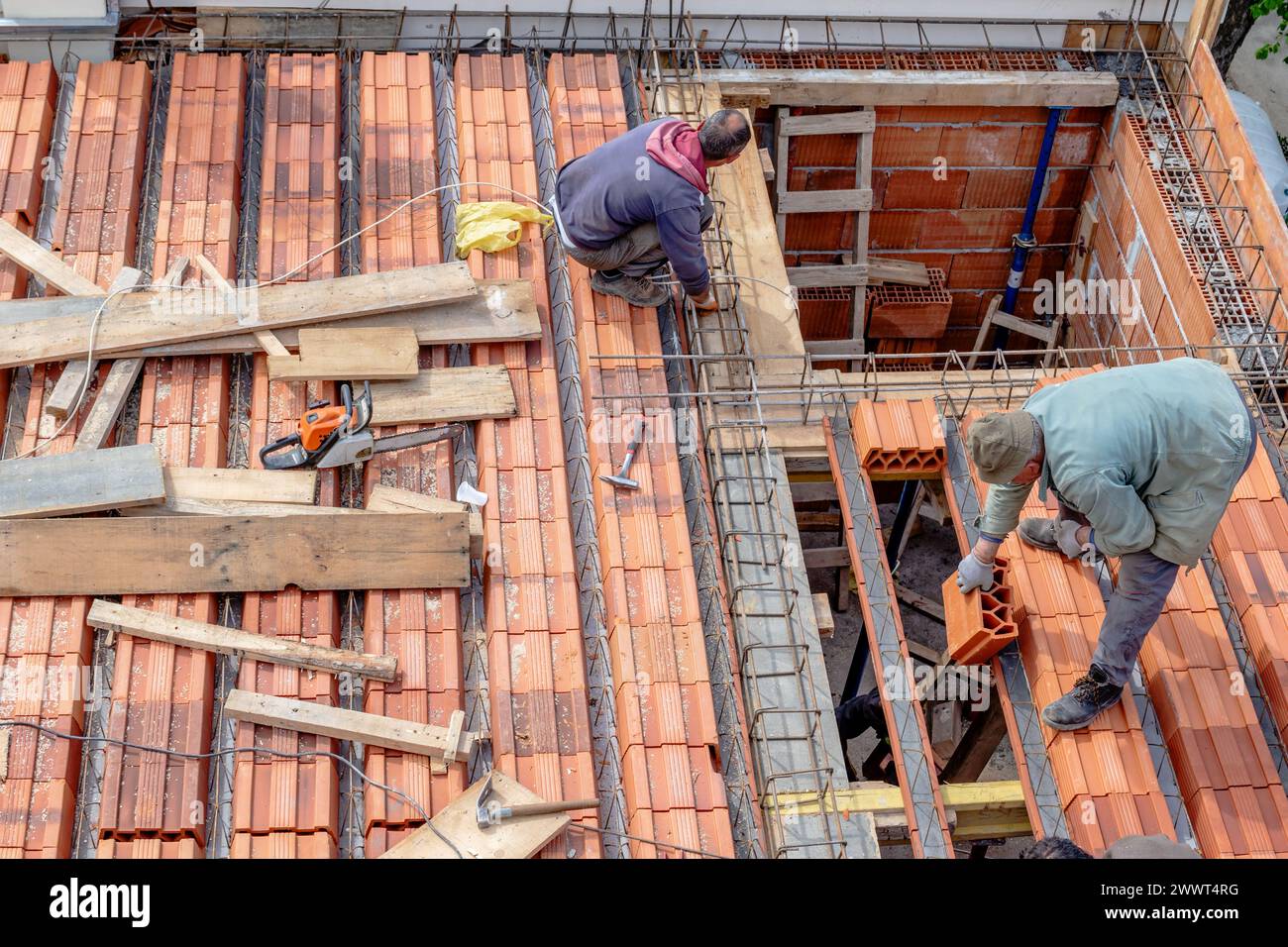 Gli operai edili sistemano i mattoni prima di versare la lastra del tetto. Fabbricazione della cassaforma in legno e installazione del rinforzo in acciaio. Foto Stock
