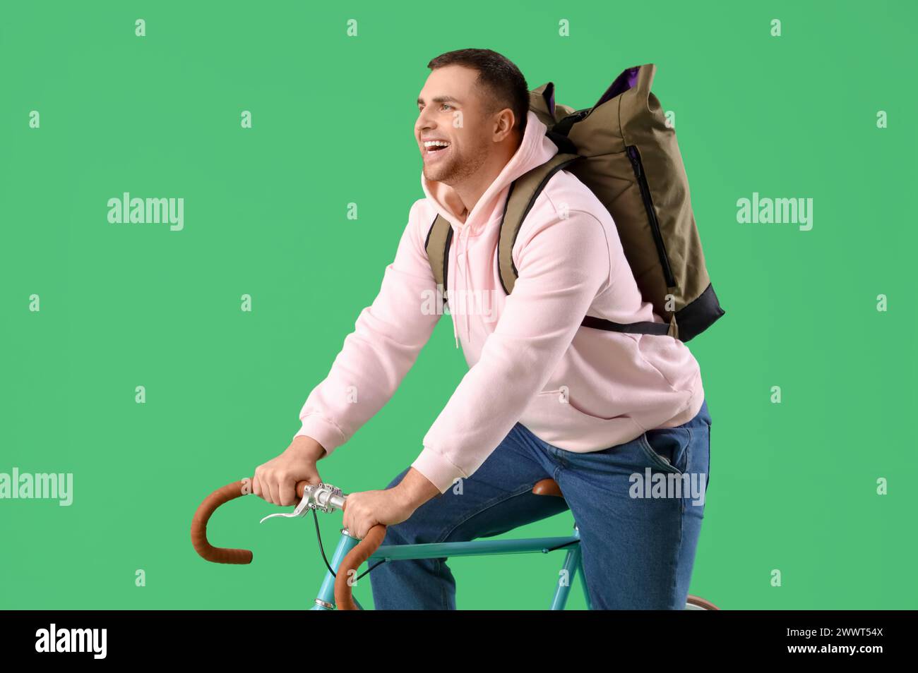 Turista maschile con zaino in bicicletta su sfondo verde Foto Stock