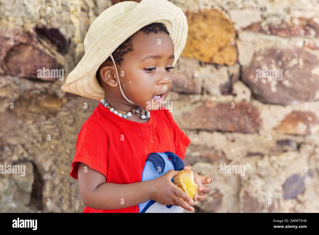 giovane ragazza africana affamata che mangia biscotti, vita di villaggio in una zona remota Foto Stock