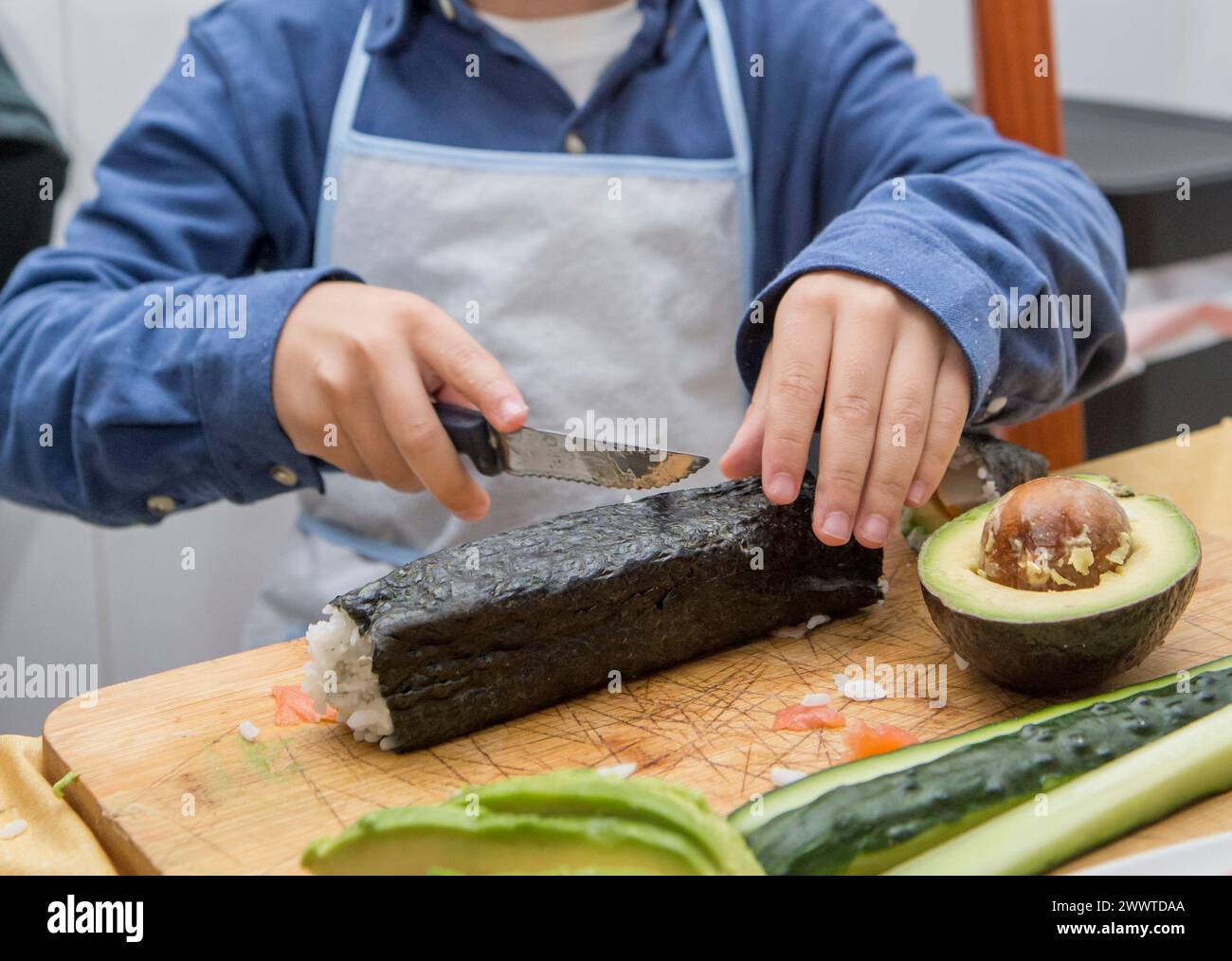 Bambino che prepara sushi fatto in casa. Attività in cucina adatte ai bambini Foto Stock